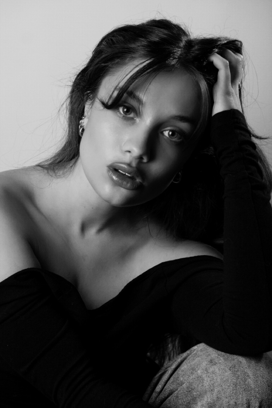 Black and white portrait of Merivelle, one hand in her hair, looking to camera.