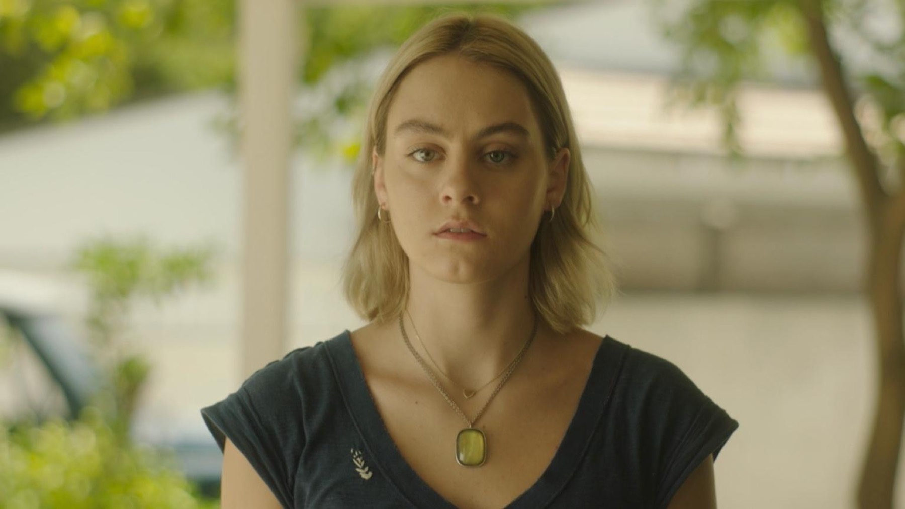 A young woman outdoors in daylight, looking directly to camera.